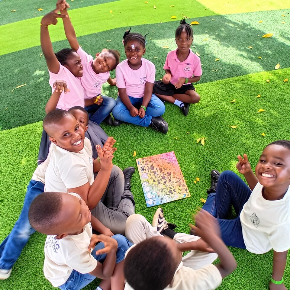 Smiling Atlantic Academy pupils enjoying a puzzle activity outdoors